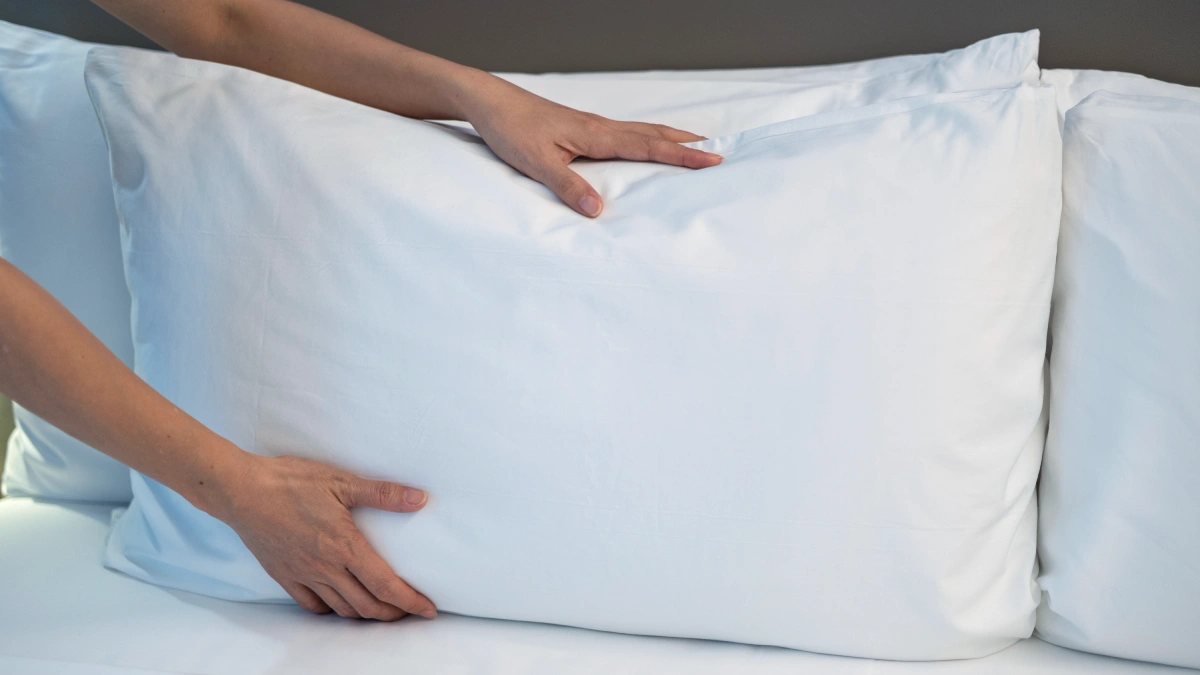 almohada de plumas deformándose al presionar mostrando falta de soporte