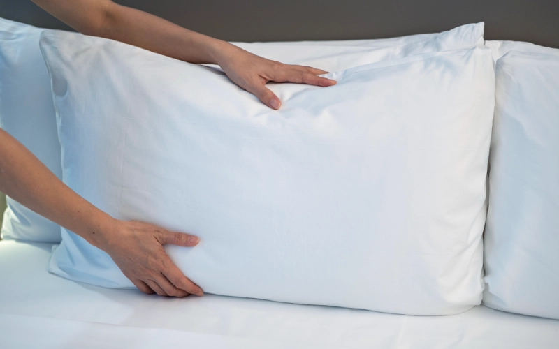 almohada de plumas deformándose al presionar mostrando falta de soporte