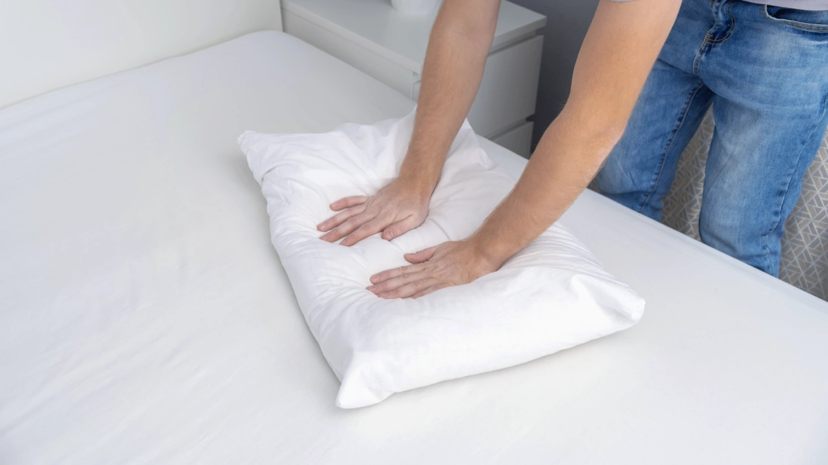 almohada de plumas aplastándose con el peso mostrando pérdida de soporte