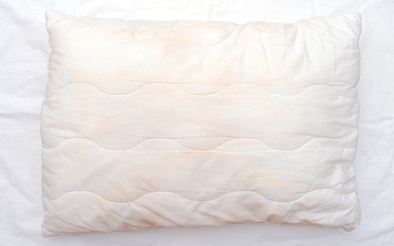 Almohada vieja y aplastada sobre una cama, señal de que toca cambiarla