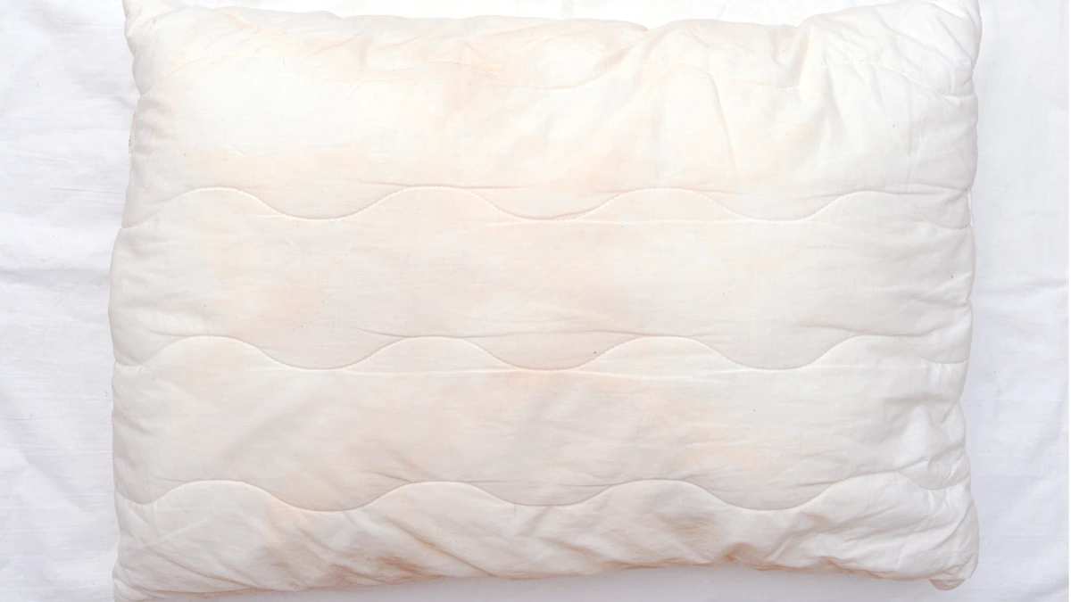 Almohada vieja y aplastada sobre una cama, señal de que toca cambiarla