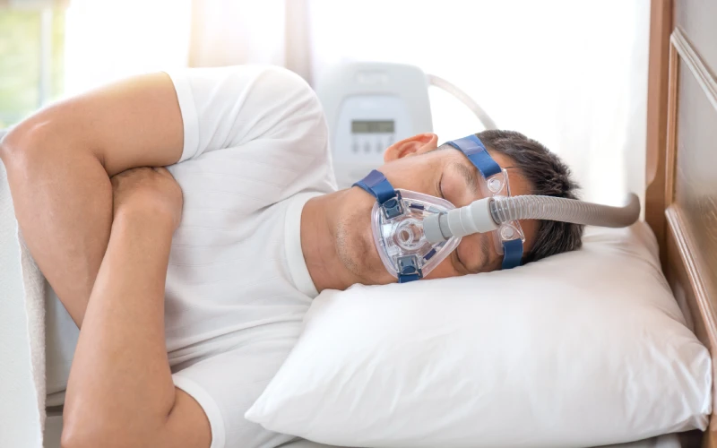 Hombre durmiendo de lado con mascarilla CPAP para la apnea del sueño