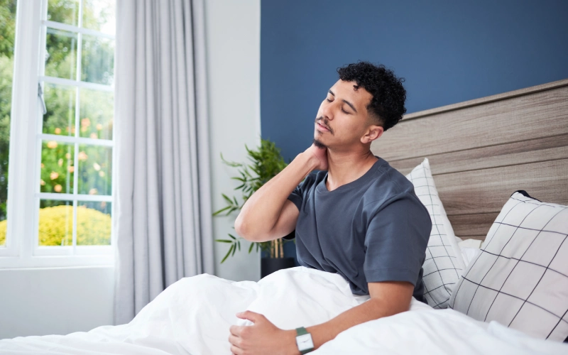 hombre en la cama despertando con dolor de cuello por uso de una almohada incorrecta